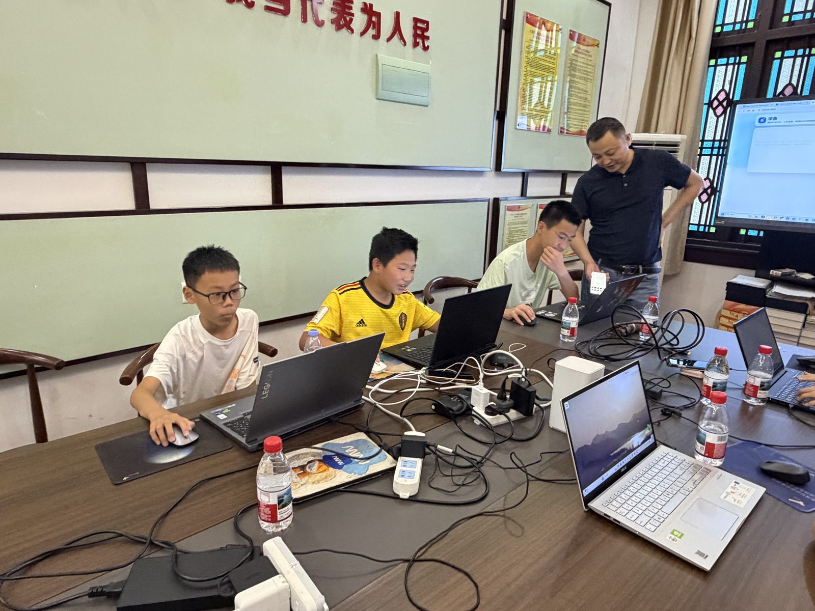 孩子们在电脑前独立制作项目，导师在旁支持