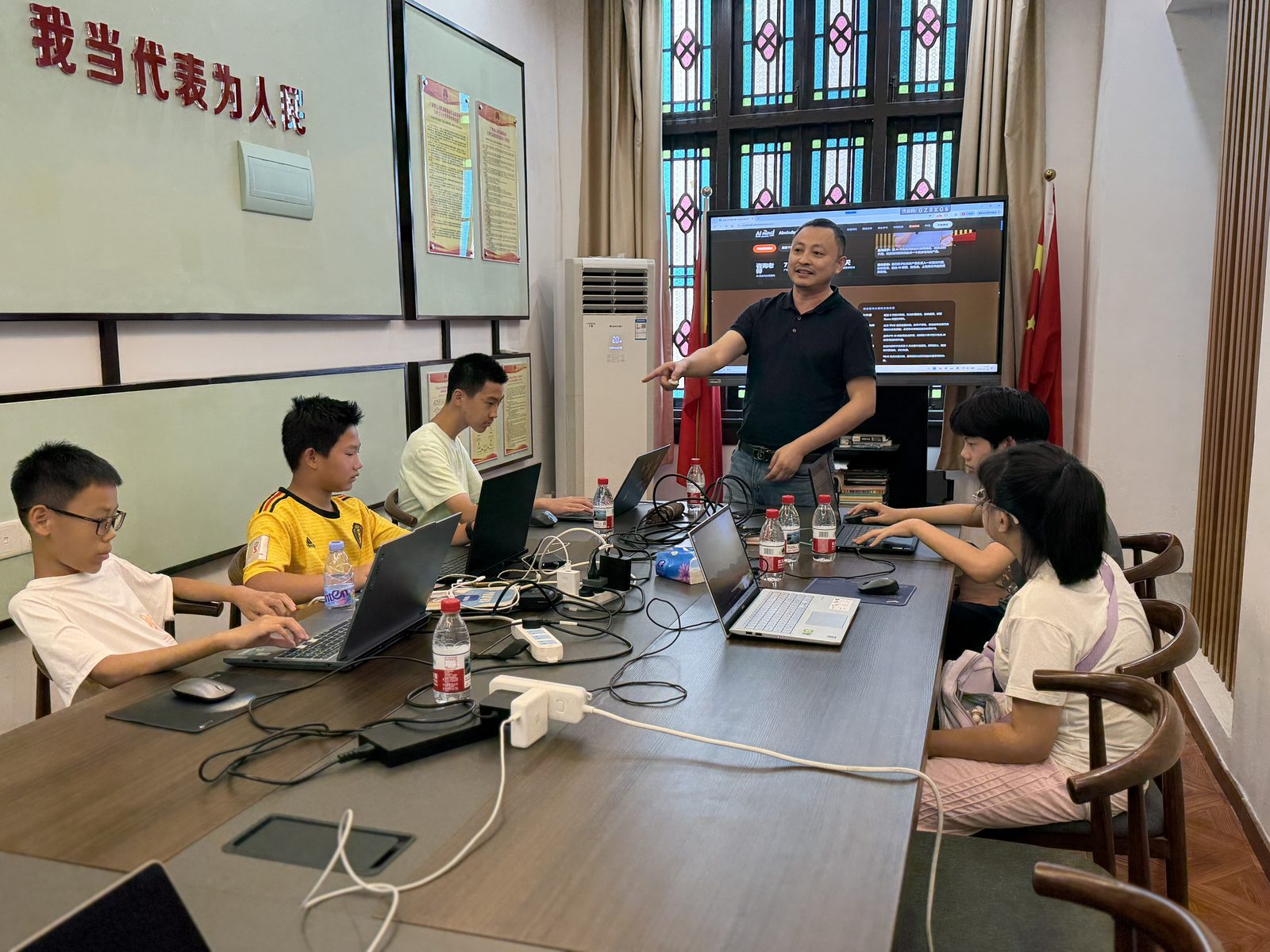 创业营中孩子们围坐在工作台前推进自己的 AI 项目